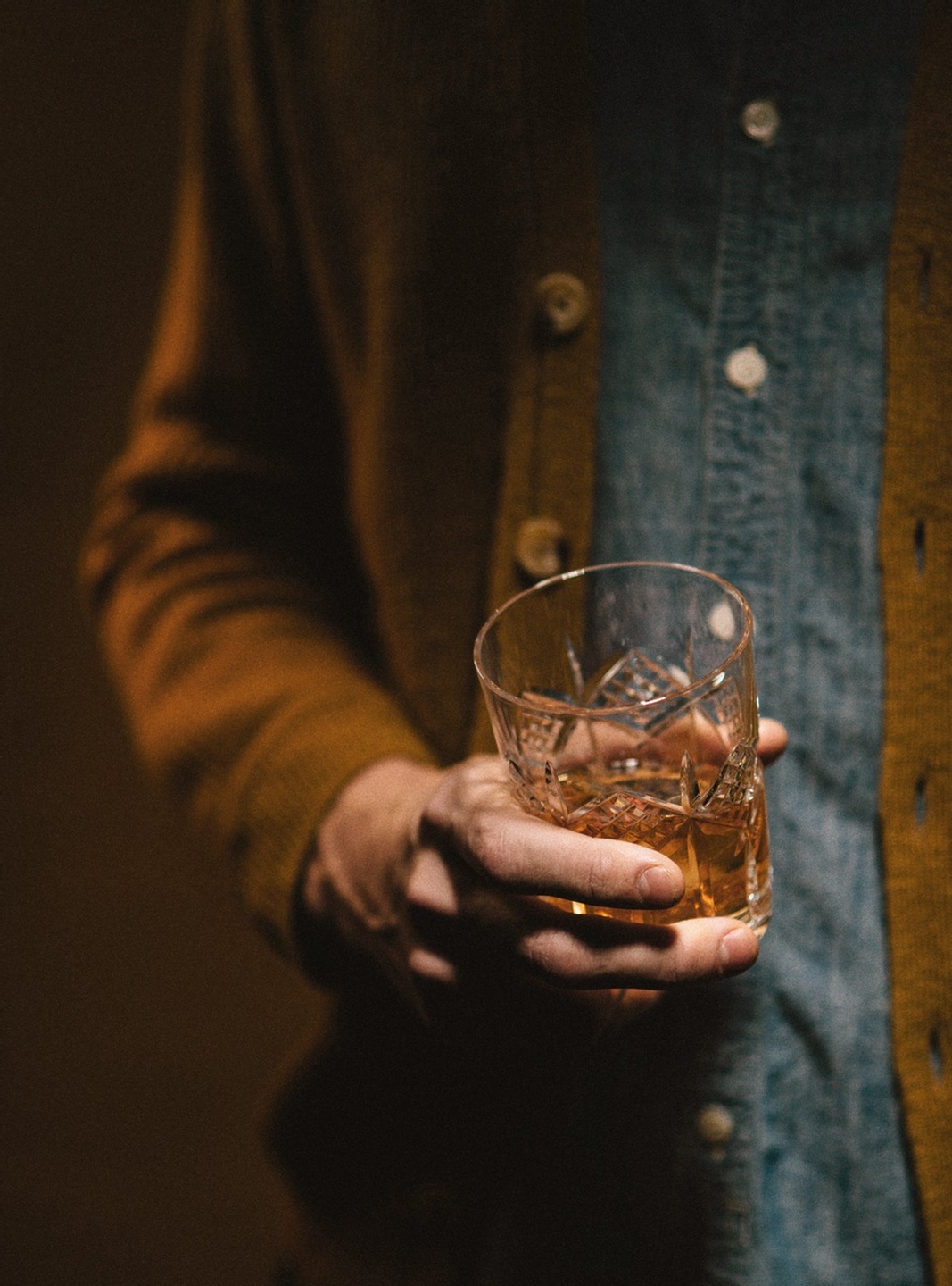 Man holding a drink in a dark room