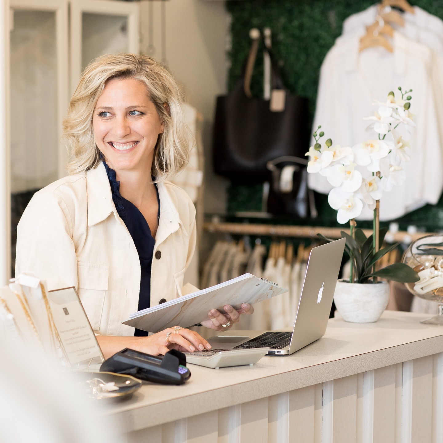 Ciara Stockeland, business coach and founder of The Boutique Workshop, at a checkout counter in a boutique clothing store.