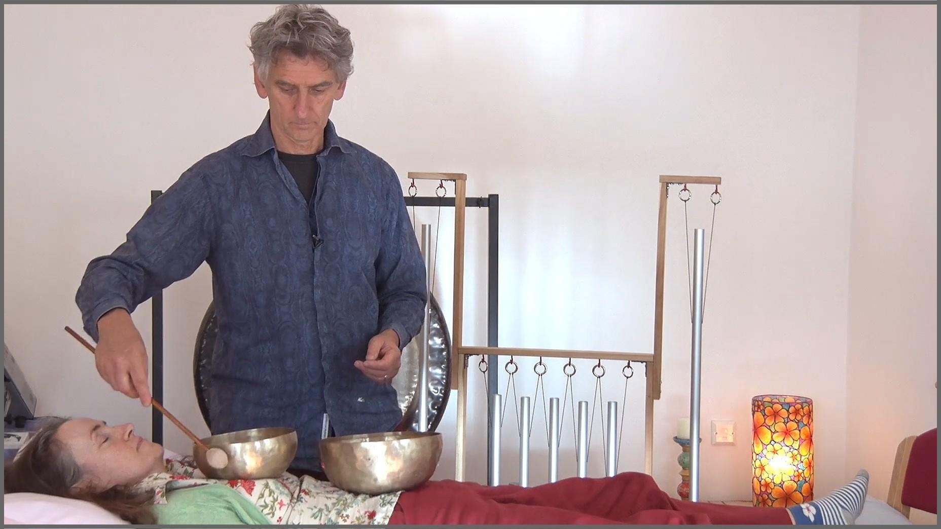 Sound Healing Practitioner using Tibetan Singing Bowls on his client in a healing room