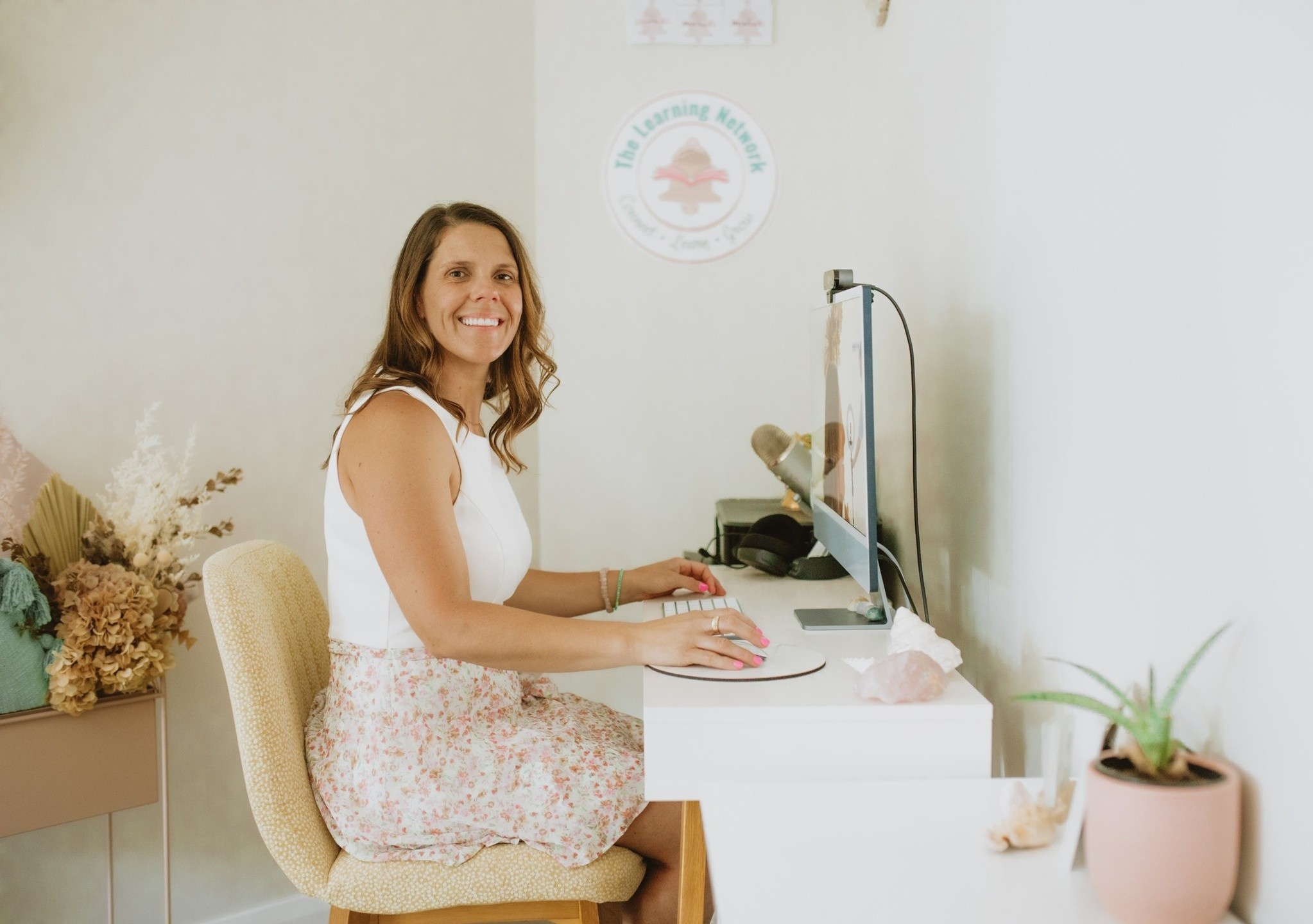 Community and Family Studies (CAFS), entrepreneur and education coach Kelly Bell sitting at a computer and smiling at the camera