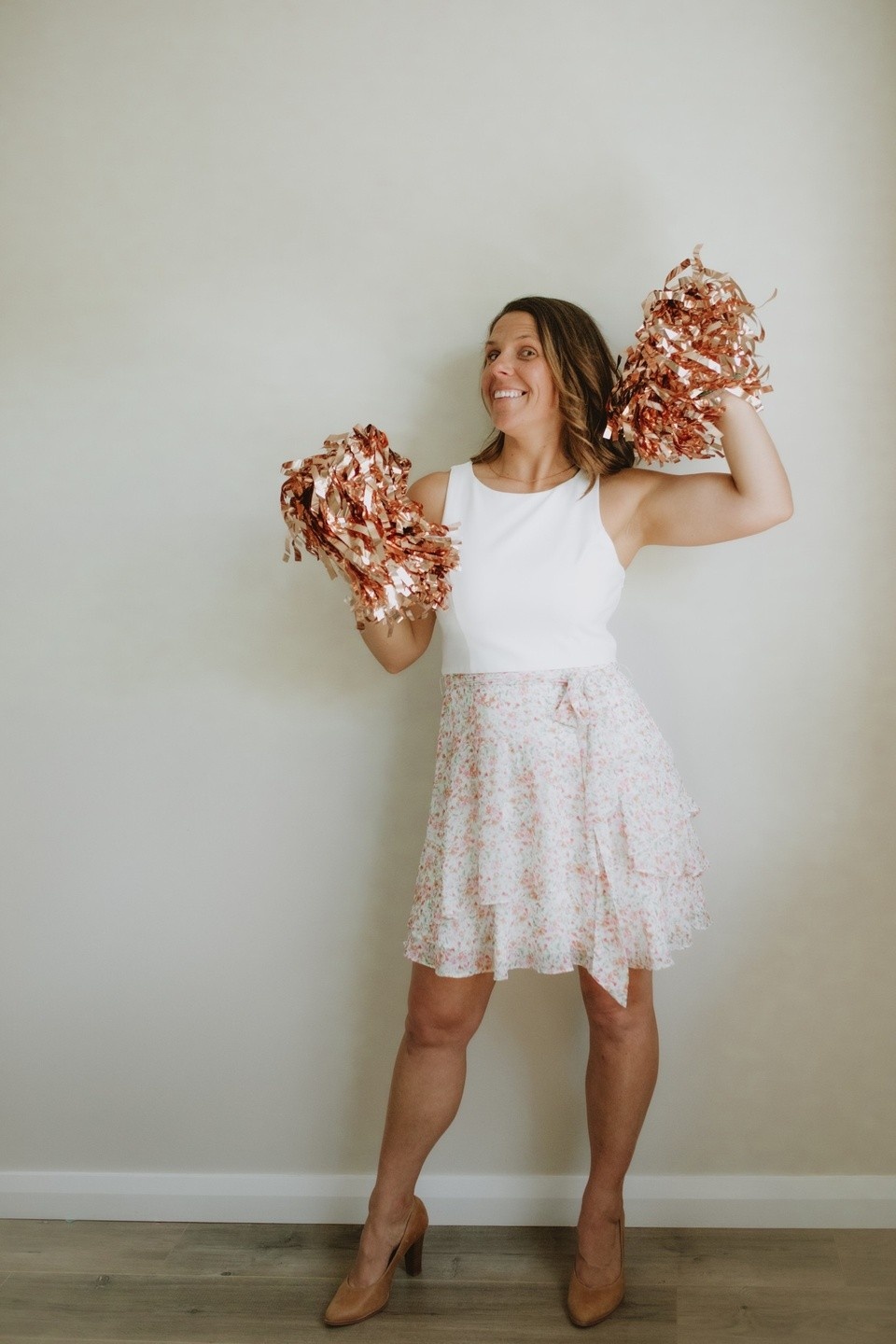 Community and Family Studies (CAFS) and education coach Kelly Bell standing with her arms raised holding pom poms and smiling