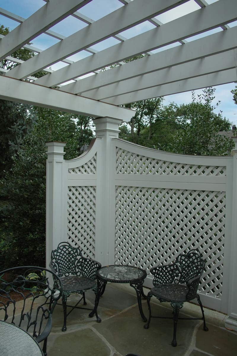 White painted diagonal privacy trelliswork set as side walls for portal pergola.