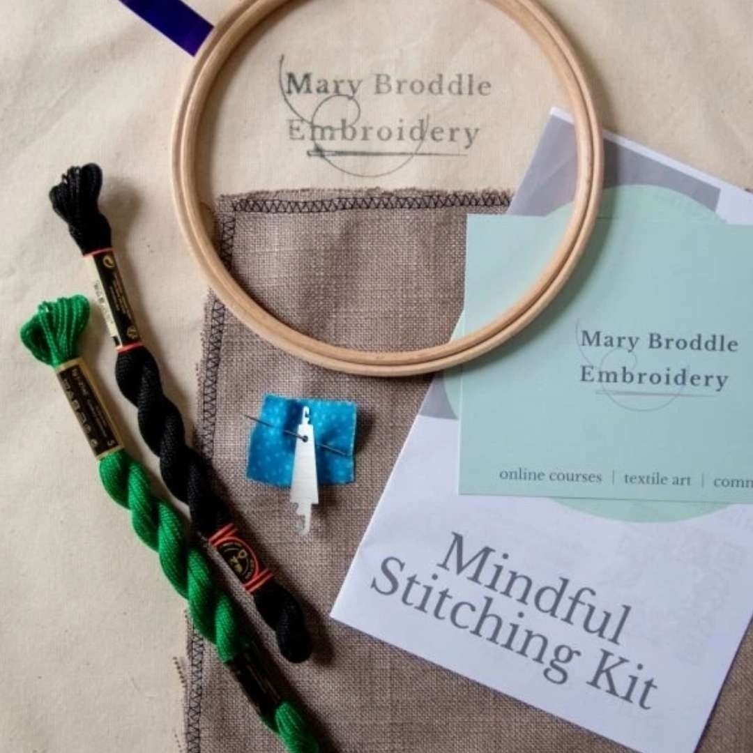 Mary Broddle Embroidery kit and its contents including green and black threads, needle, text instructions and an embroidery hoop