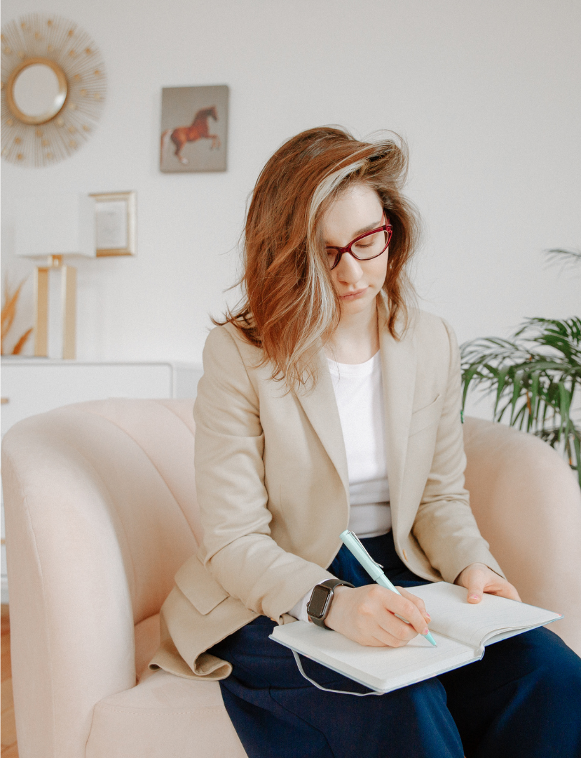 woman in blazer writing in a journal