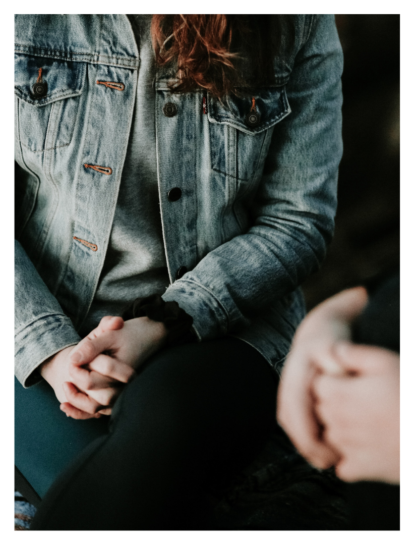 woman sitting with hands in lap wearing jean jacket