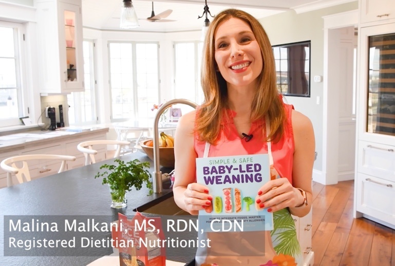 Malina Malkani holding her best selling book on Baby-led Weaning