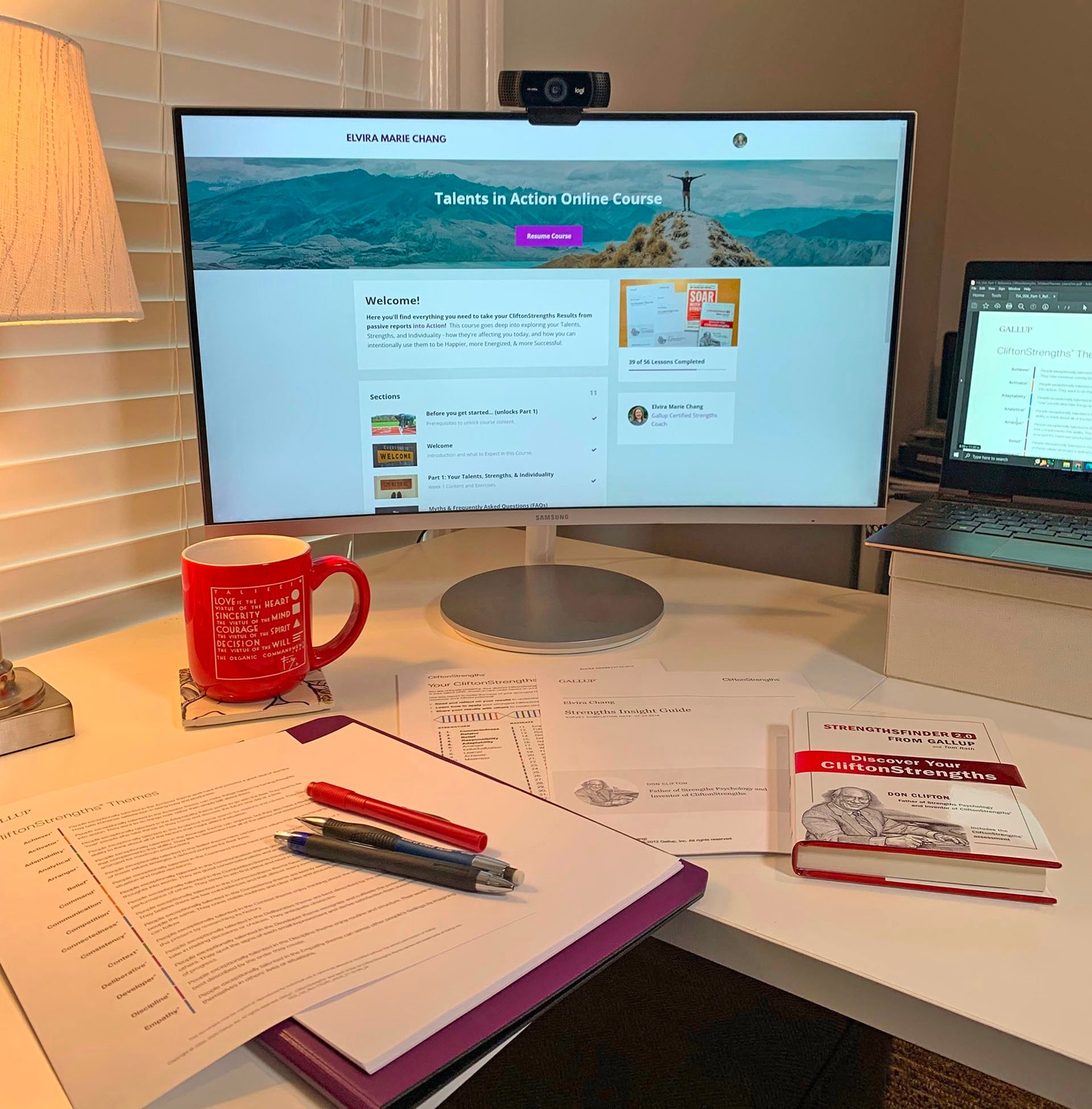 Desk with StrengthsFinder book, reports, and screen showing online course