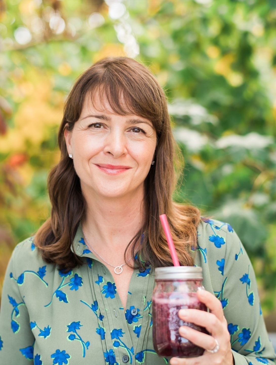 Headshot of Vanessa Bond, brunette woman holding smoothie