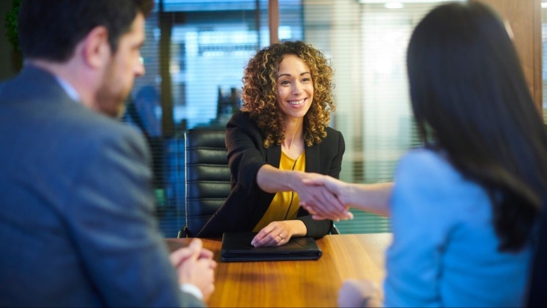 interviewee with 2 interviewers shaking hands