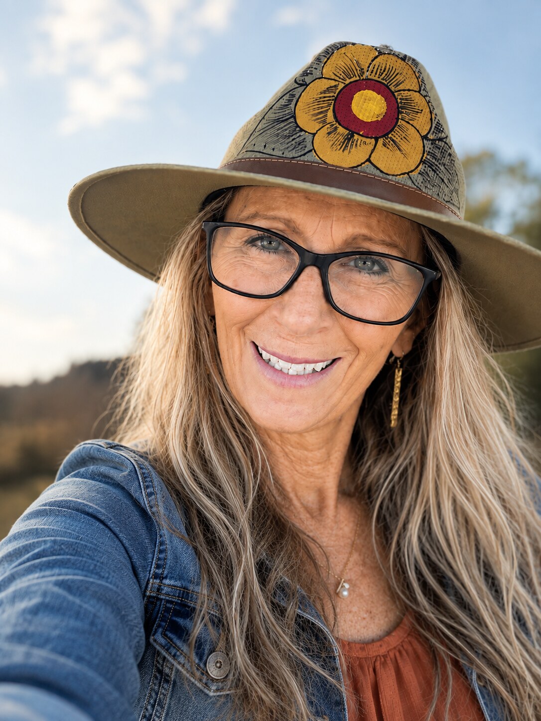 Jackie L Armstrong smiling outdoors in her signature flowered hat