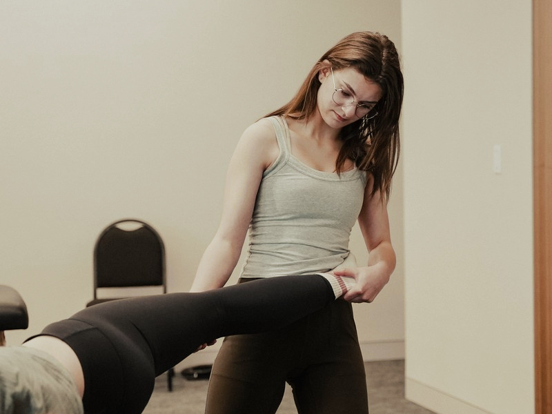 A student taking a classmate's leg into a stretch