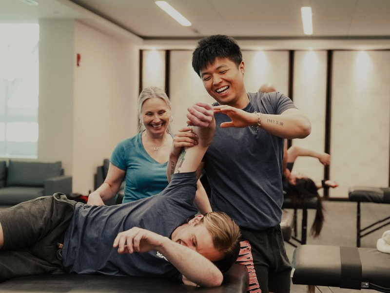 Students laughing while practising a shoulder stretch