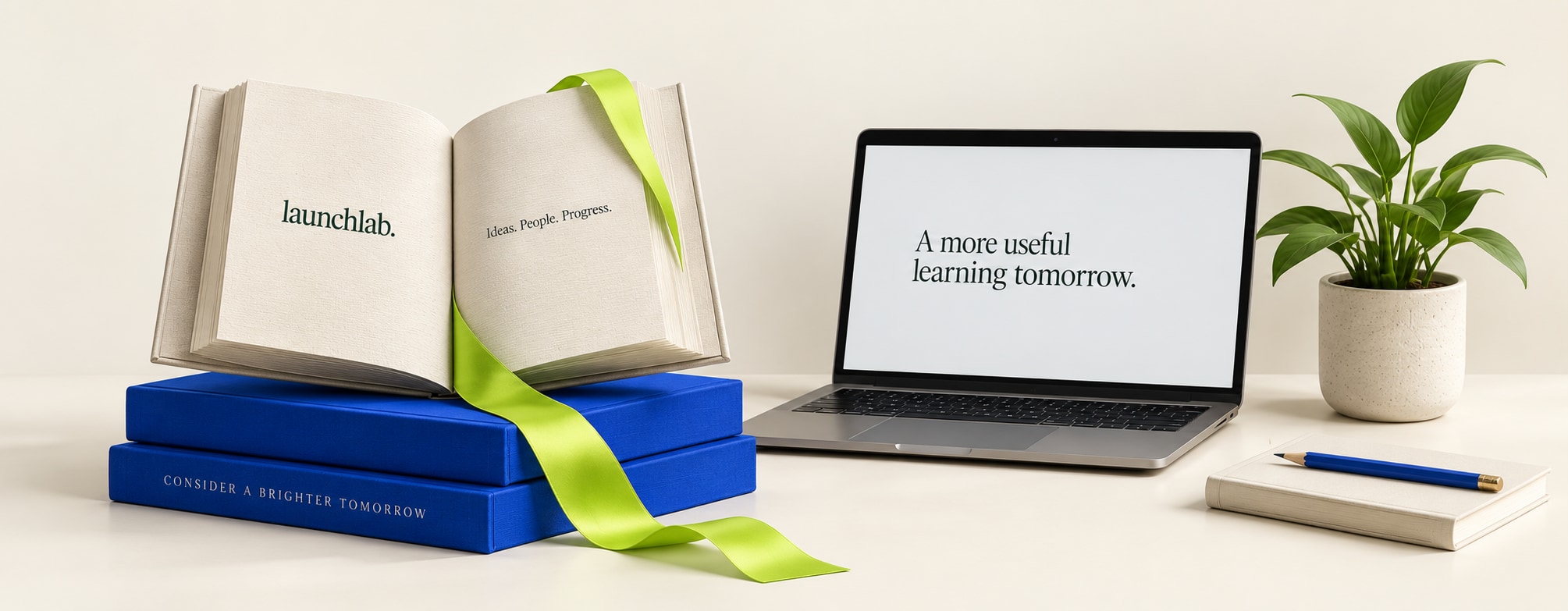 Open linen book, cobalt books, lime ribbon and a laptop in the LaunchLab studio