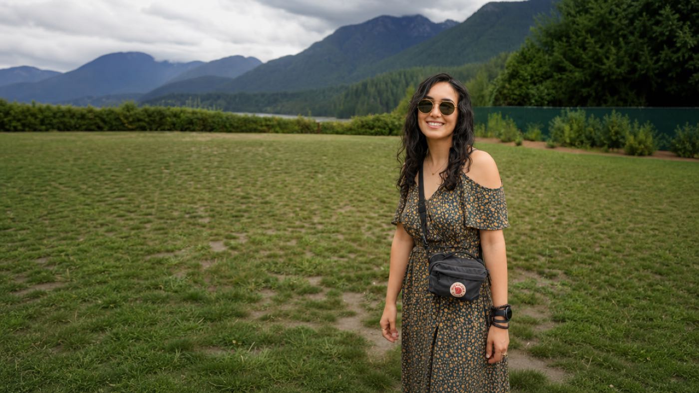 Yasi smiling in a field with mountains behind her