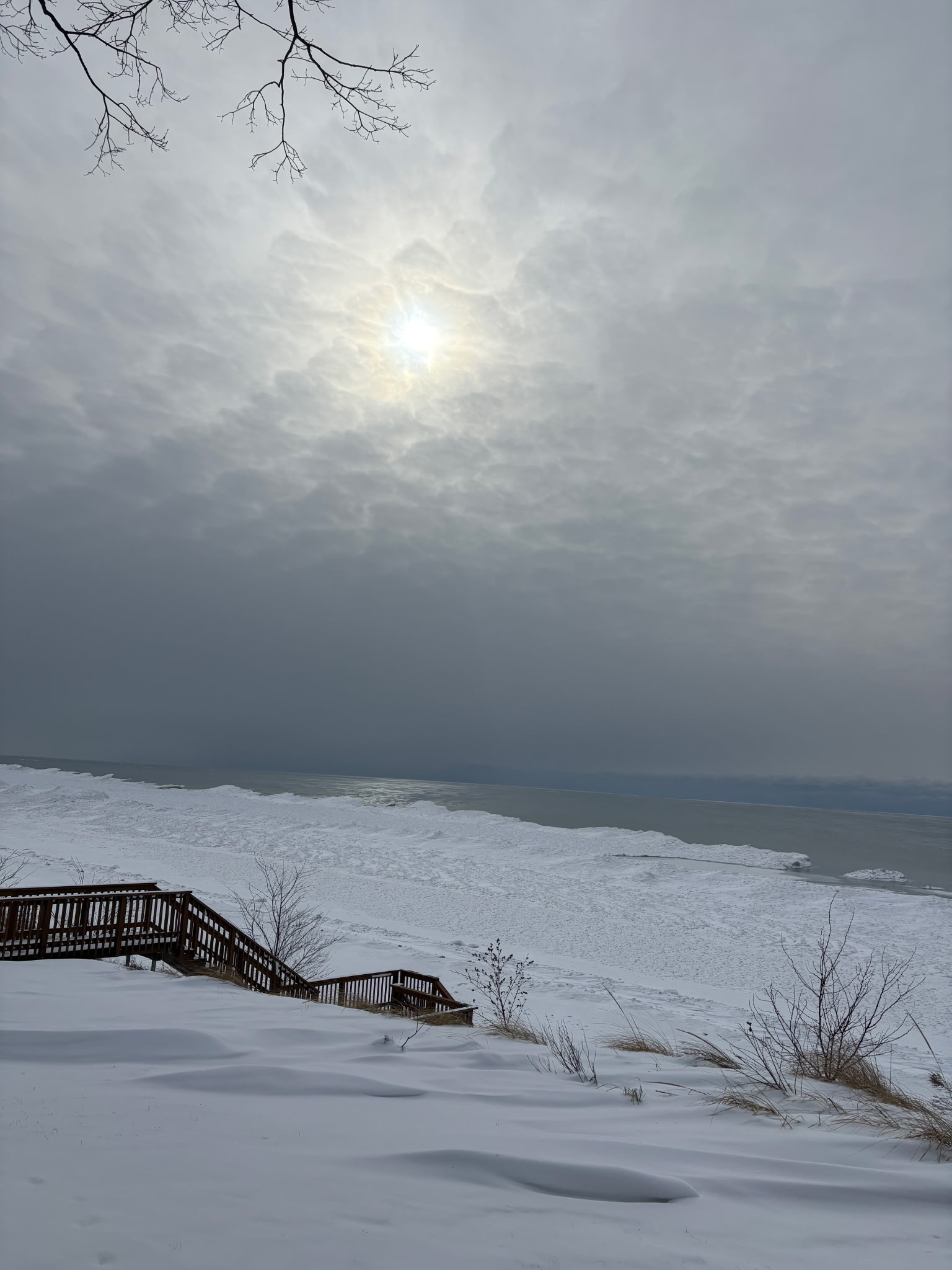 Snow-covered Lake Michigan shoreline with stairs and winter sun