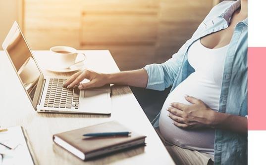 Pregnant Women at Computer Holding Belly