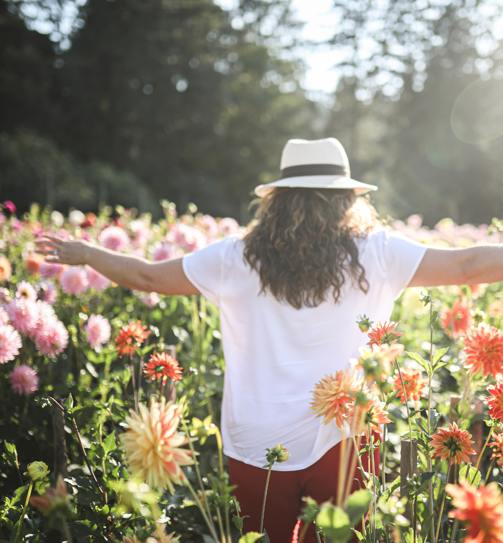 woman walking through a field of flowers spreading her ams out with joy